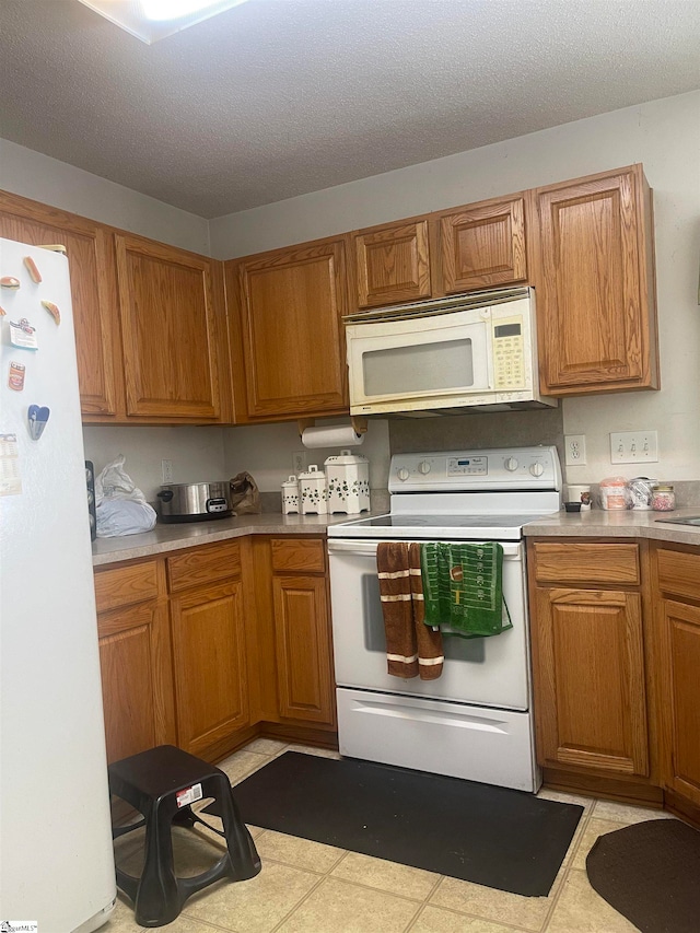 kitchen featuring a textured ceiling, light tile patterned floors, and white appliances