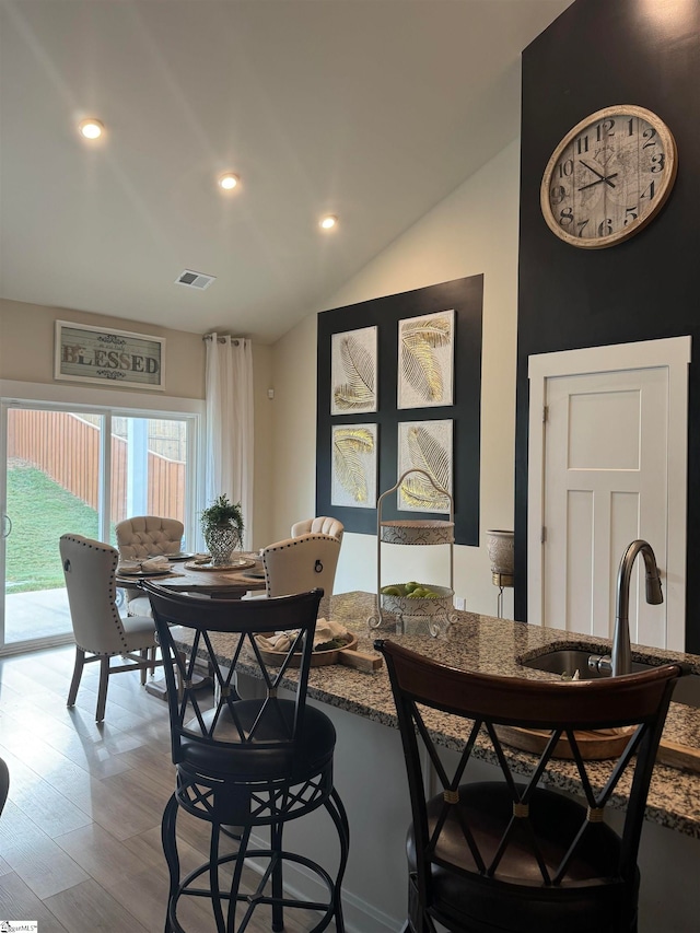 dining area with lofted ceiling, hardwood / wood-style floors, and sink