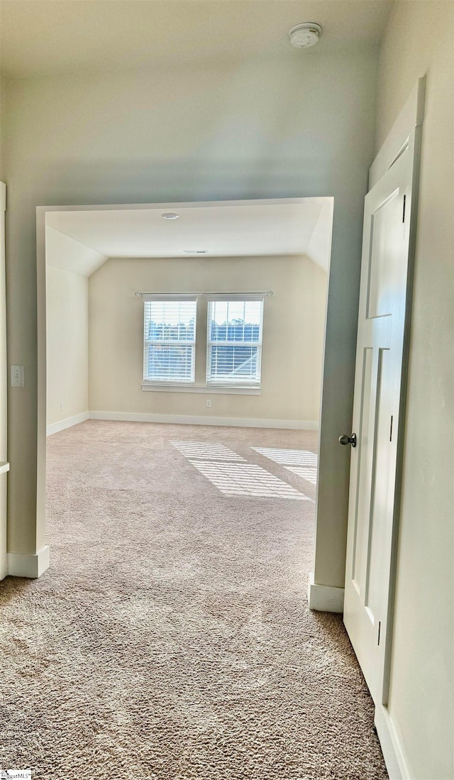 carpeted spare room featuring vaulted ceiling