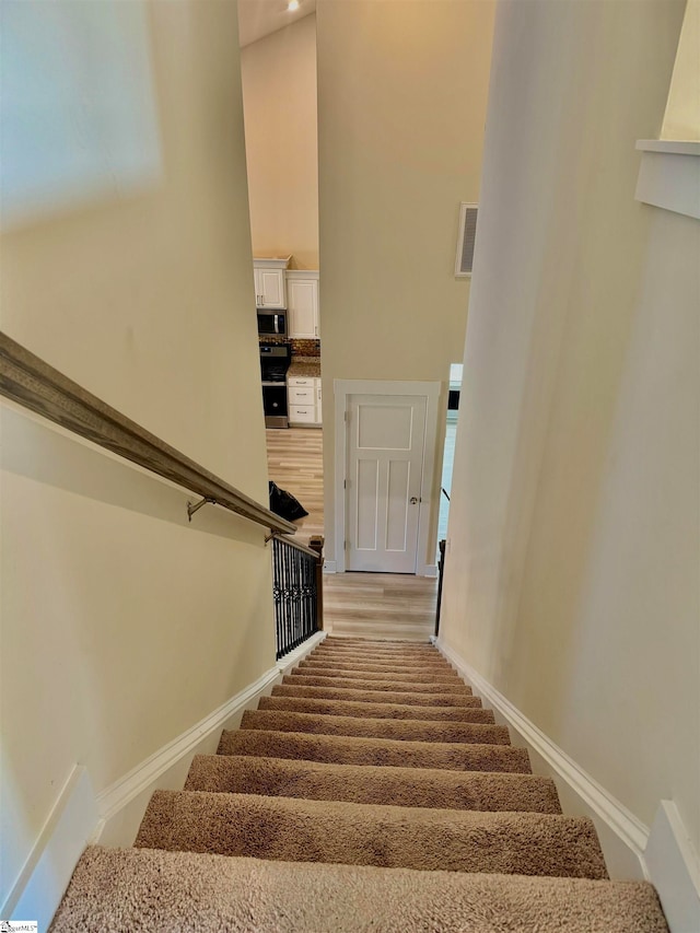 stairway with a high ceiling and hardwood / wood-style flooring