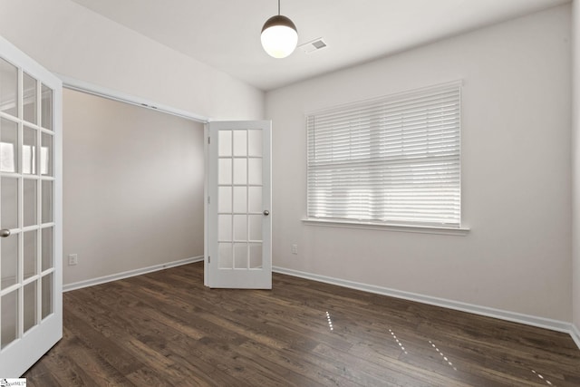 spare room featuring french doors and dark wood-type flooring