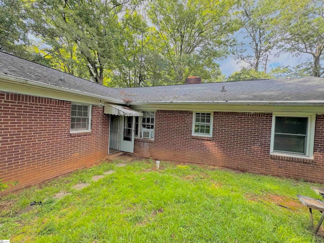 rear view of house with cooling unit and a lawn