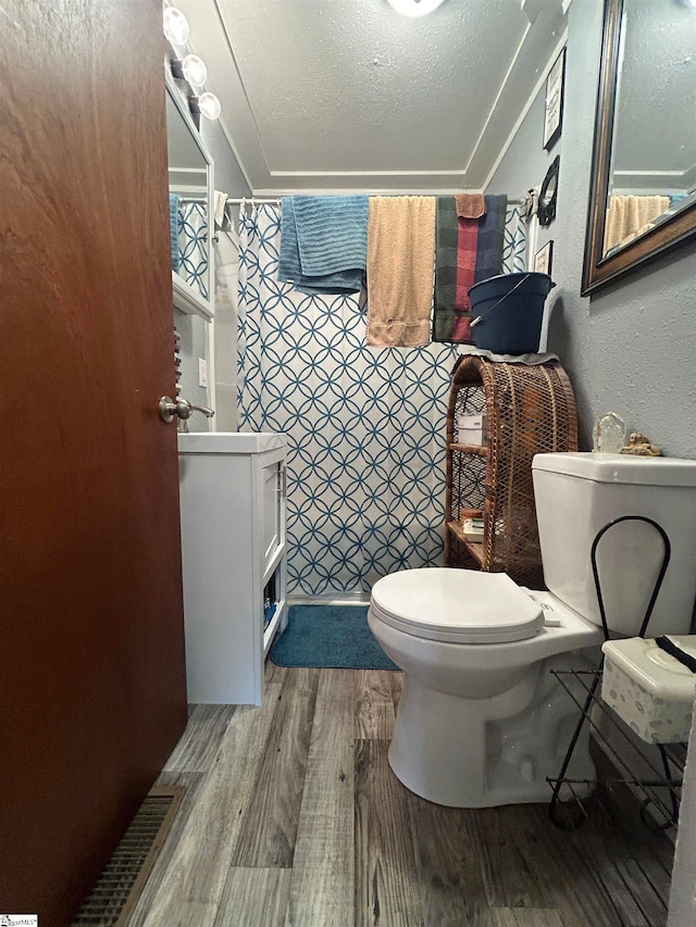 bathroom with toilet, a textured ceiling, and wood-type flooring