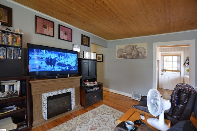 living room with light hardwood / wood-style flooring, wooden ceiling, a fireplace, and crown molding