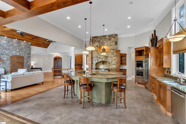 kitchen with beam ceiling, a breakfast bar area, a spacious island, sink, and stainless steel appliances