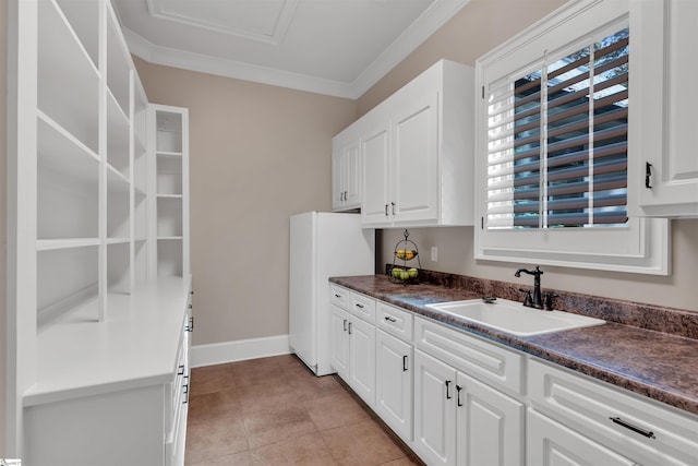 kitchen featuring ornamental molding, white cabinets, sink, and light tile patterned floors