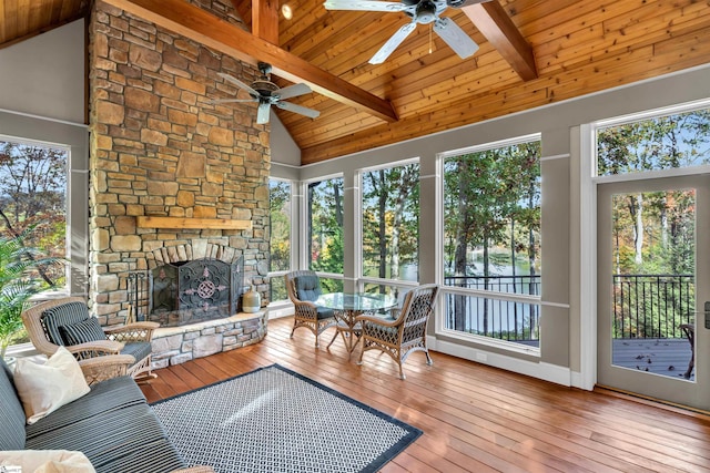 sunroom with ceiling fan, wood ceiling, vaulted ceiling with beams, and a fireplace