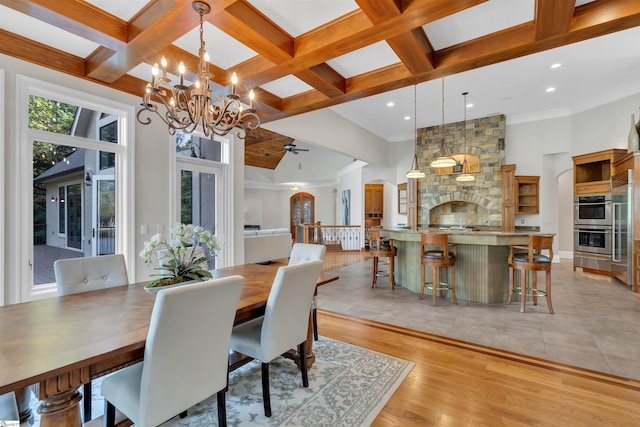 dining space with beam ceiling, ornamental molding, ceiling fan with notable chandelier, light hardwood / wood-style floors, and coffered ceiling