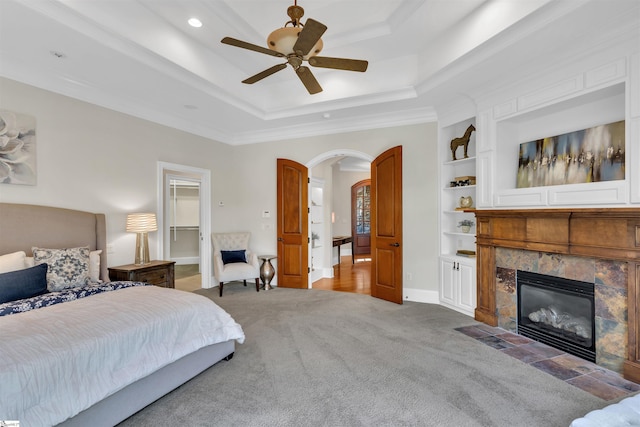 bedroom with ceiling fan, a spacious closet, ornamental molding, carpet floors, and a tile fireplace