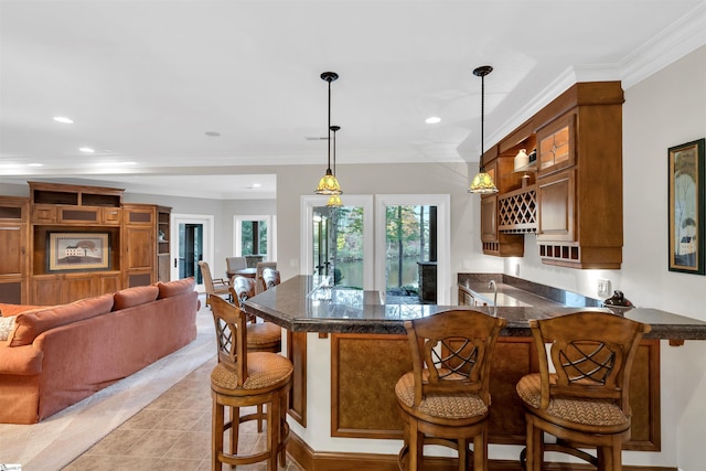 kitchen with kitchen peninsula, ornamental molding, a kitchen bar, decorative light fixtures, and light tile patterned floors