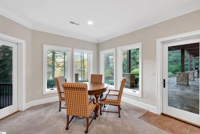 dining area featuring light carpet, ornamental molding, and plenty of natural light