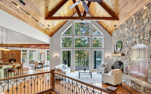 living room featuring beam ceiling, a healthy amount of sunlight, and high vaulted ceiling