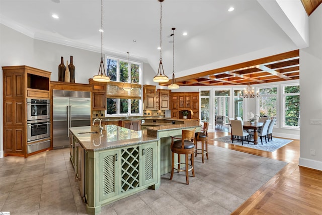 kitchen featuring a kitchen breakfast bar, a large island, sink, decorative light fixtures, and appliances with stainless steel finishes