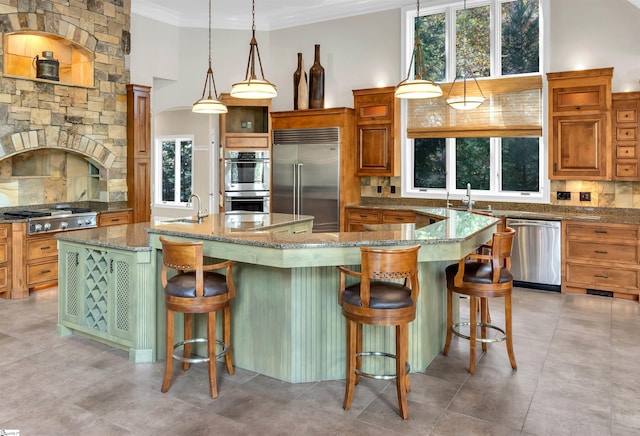 kitchen with decorative backsplash, a kitchen island with sink, stainless steel appliances, and a wealth of natural light