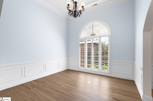 unfurnished room featuring an inviting chandelier, hardwood / wood-style floors, and crown molding