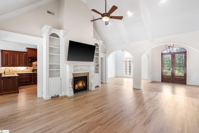 unfurnished living room with ceiling fan, a high end fireplace, high vaulted ceiling, light hardwood / wood-style floors, and sink