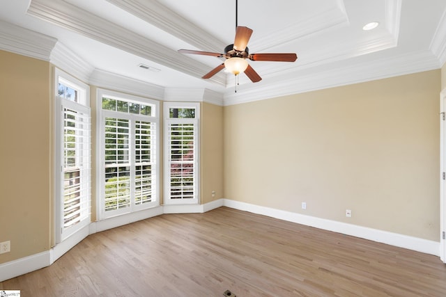 spare room with crown molding, a tray ceiling, light wood-type flooring, and ceiling fan