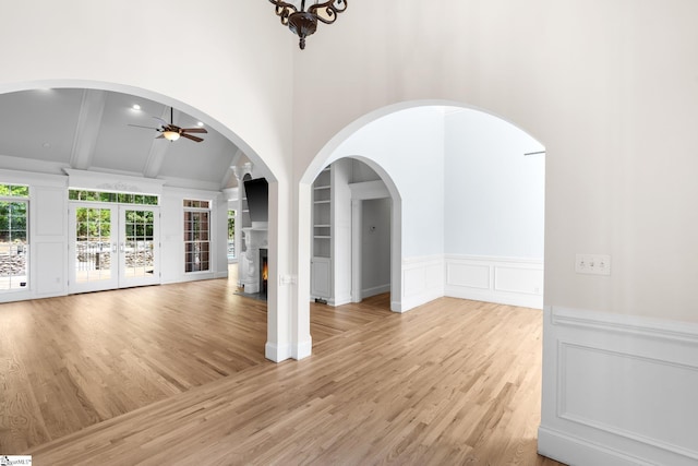 unfurnished living room with french doors, light hardwood / wood-style flooring, lofted ceiling with beams, and ceiling fan