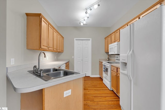 kitchen with light brown cabinets, kitchen peninsula, light hardwood / wood-style flooring, sink, and white appliances