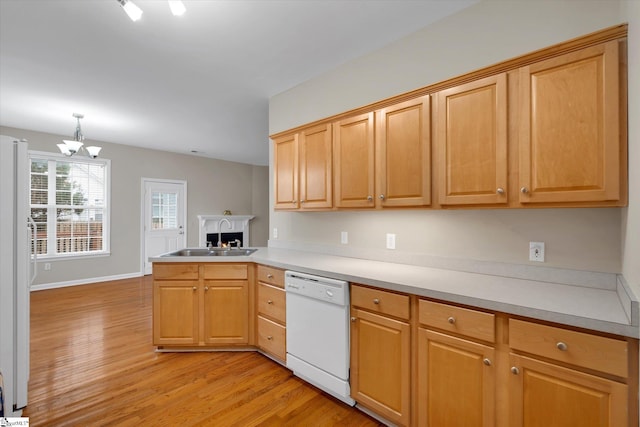 kitchen with white appliances, sink, light wood-type flooring, and decorative light fixtures