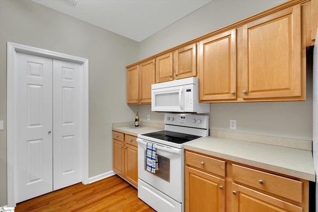 kitchen with light hardwood / wood-style floors, white appliances, and light brown cabinets