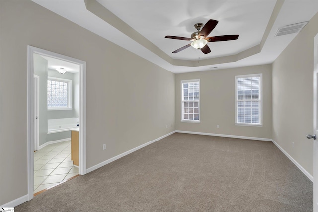 carpeted spare room featuring ceiling fan and a tray ceiling