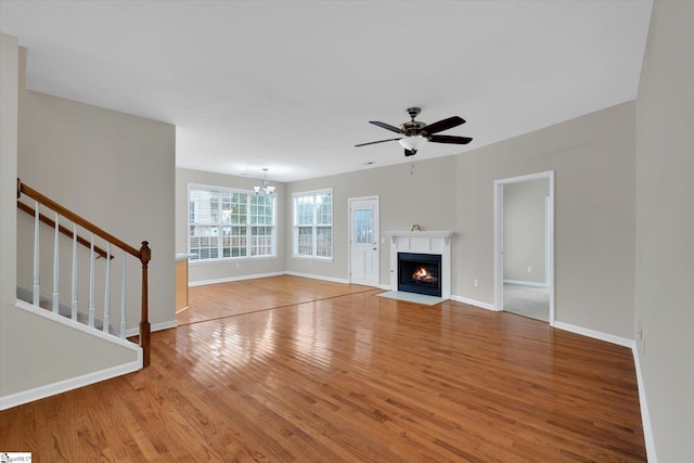 unfurnished living room with hardwood / wood-style floors and ceiling fan with notable chandelier