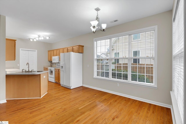 kitchen with white appliances, kitchen peninsula, light hardwood / wood-style floors, decorative light fixtures, and a notable chandelier