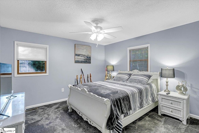 bedroom with dark colored carpet, a textured ceiling, and ceiling fan