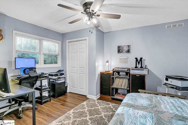 bedroom featuring a textured ceiling, wood-type flooring, and ceiling fan