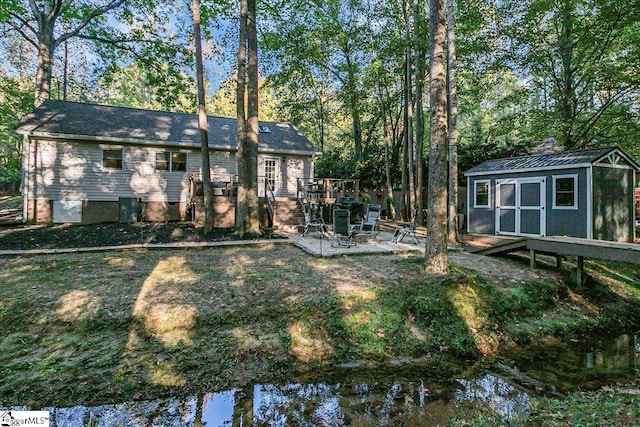 rear view of house featuring a shed and a water view