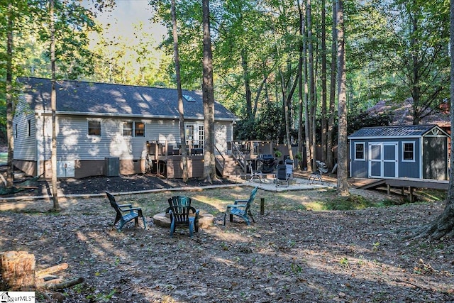 rear view of house featuring an outdoor fire pit and a shed