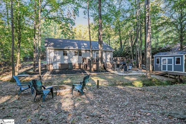 rear view of property featuring a shed, a fire pit, and a wooden deck