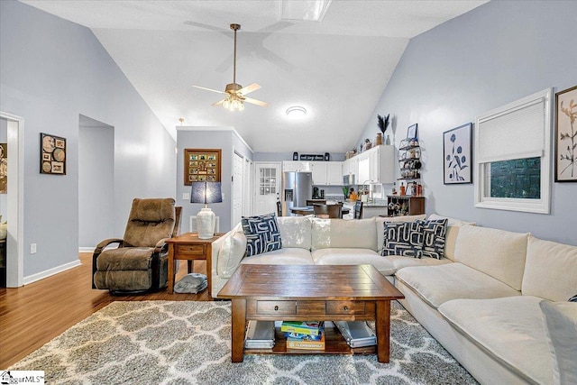 living room featuring hardwood / wood-style floors, high vaulted ceiling, and ceiling fan