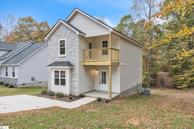 rear view of property featuring central air condition unit, a yard, and a balcony