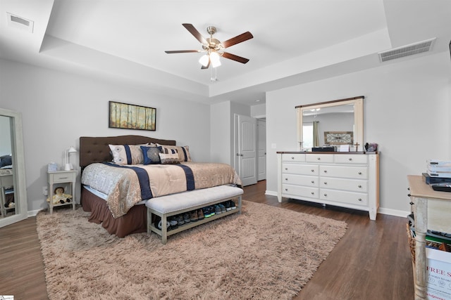 bedroom featuring dark hardwood / wood-style flooring, a raised ceiling, and ceiling fan