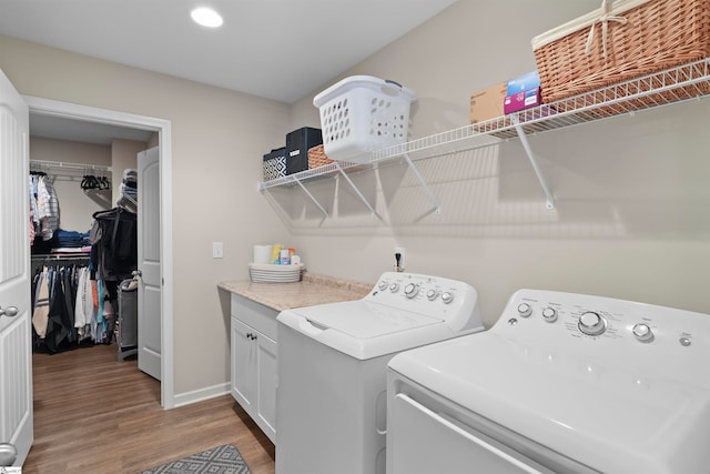 laundry area featuring washing machine and dryer, cabinets, and light wood-type flooring