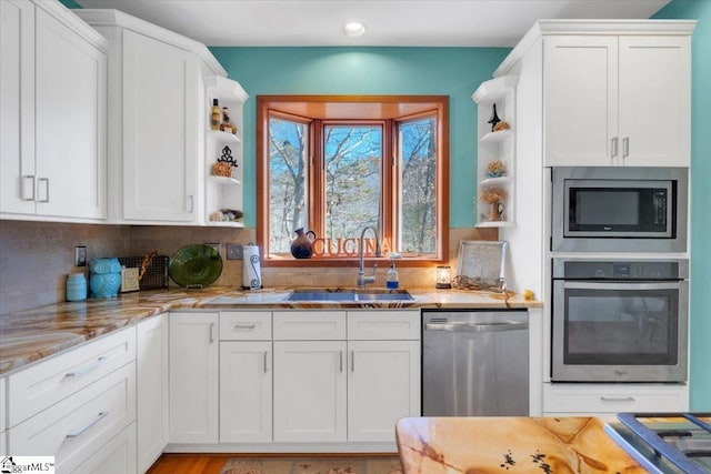 kitchen with light stone countertops, white cabinets, sink, and stainless steel appliances