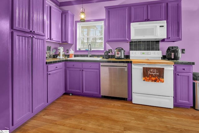 kitchen with tile countertops, light hardwood / wood-style floors, sink, hanging light fixtures, and white appliances