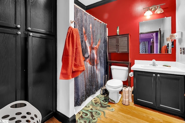 bathroom featuring wood-type flooring, toilet, ornamental molding, vanity, and walk in shower