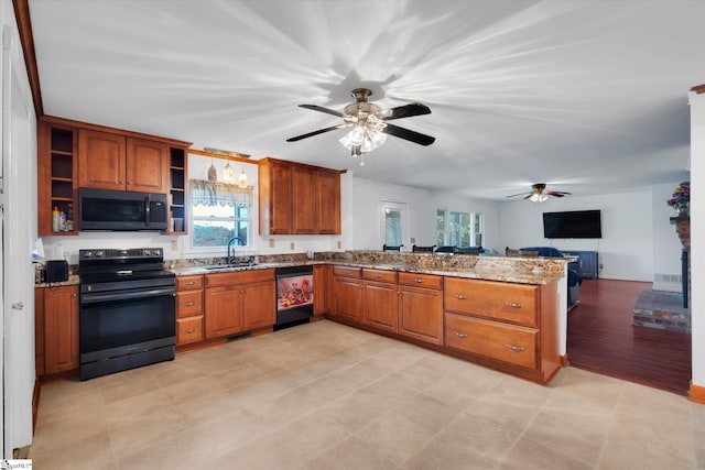 kitchen with sink, kitchen peninsula, appliances with stainless steel finishes, light stone countertops, and light wood-type flooring