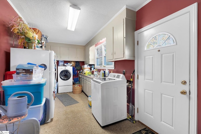 washroom featuring washing machine and dryer, cabinets, a textured ceiling, and crown molding