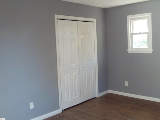 unfurnished bedroom with dark wood-type flooring and a closet