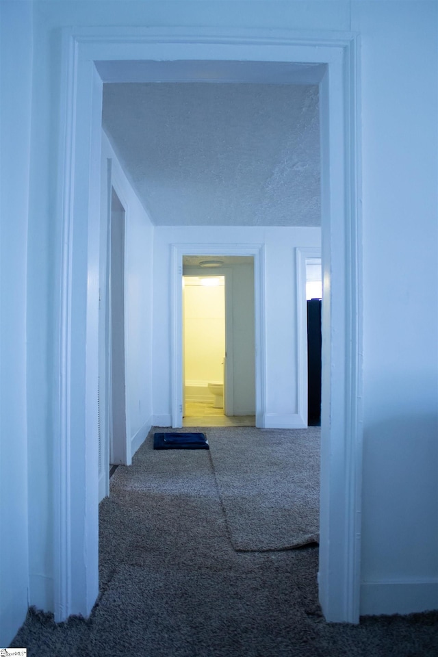 corridor featuring carpet flooring and a textured ceiling