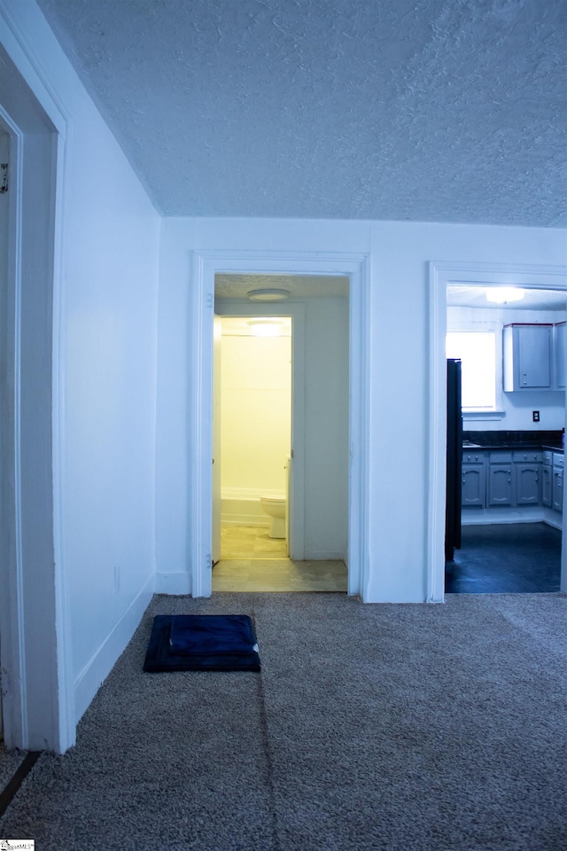 hall featuring a textured ceiling and carpet floors