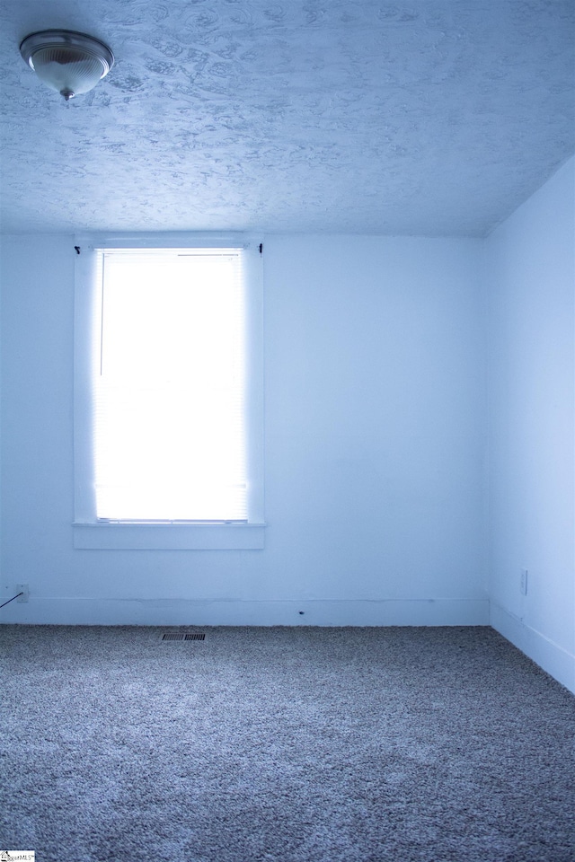 carpeted empty room featuring a textured ceiling