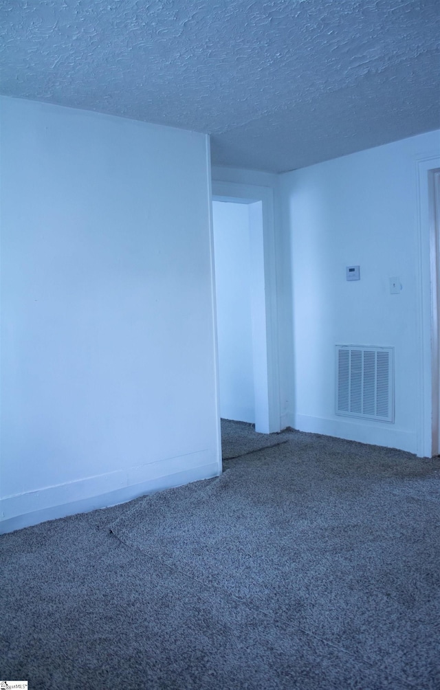 empty room with a textured ceiling and carpet flooring