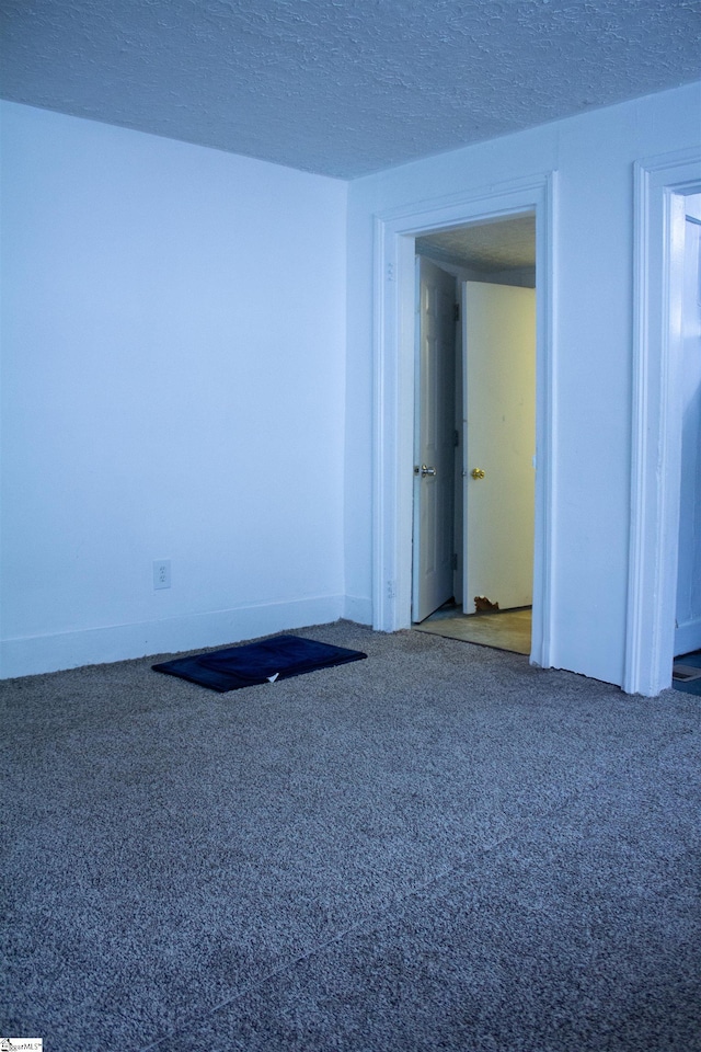 carpeted empty room featuring a textured ceiling