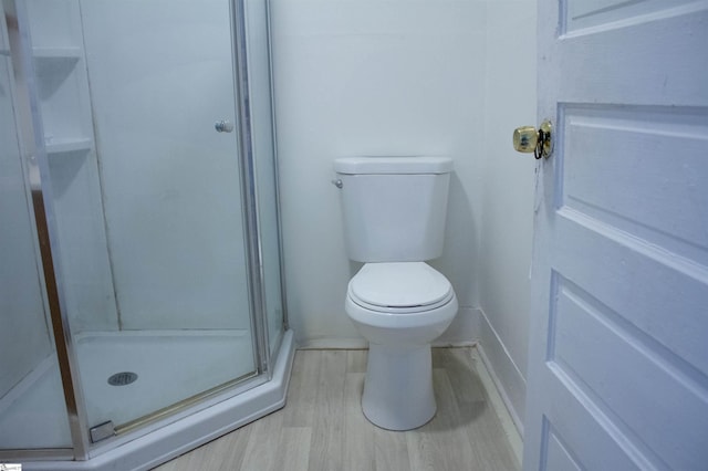 bathroom featuring hardwood / wood-style floors, a shower with door, and toilet