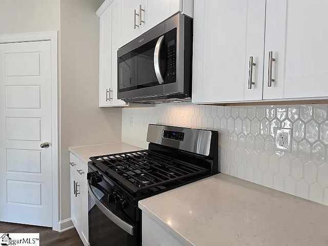 kitchen with dark hardwood / wood-style flooring, white cabinetry, appliances with stainless steel finishes, and backsplash